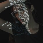 a woman wearing glasses and a t - shirt with words projected on it