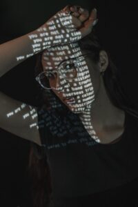 A Woman Wearing Glasses And A T - Shirt With Words Projected On It